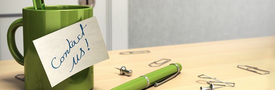 Green coffee mug and pen on light wood desk